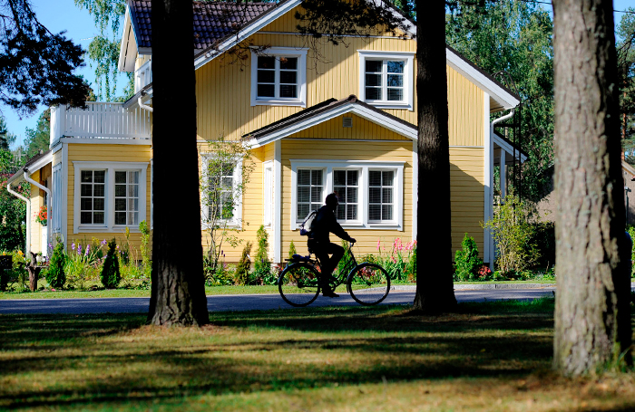 Hyvinkääläinen puutalo, jonka edessä mies ajaa pyörää.